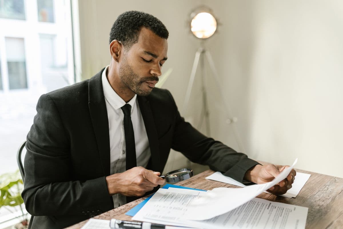 Professional reviewing paperwork with a magnifying glass for due diligence