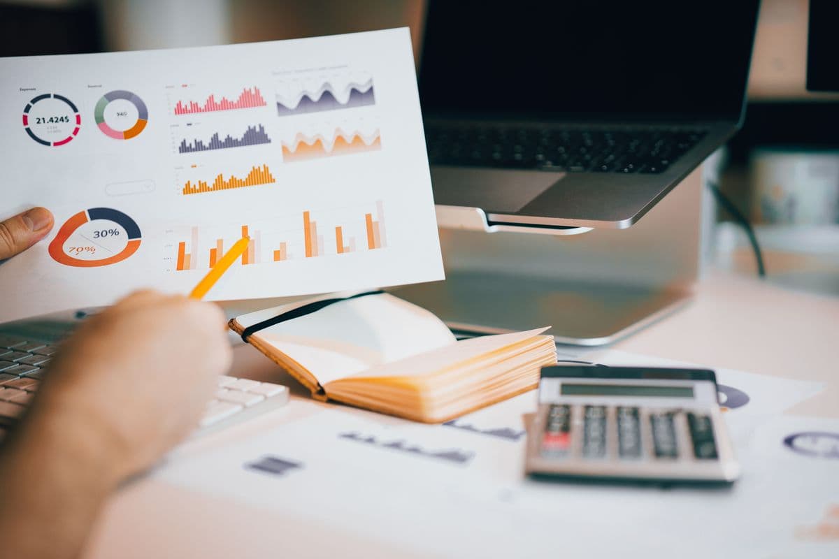 Person analyzing financial data with charts, laptop, and calculator