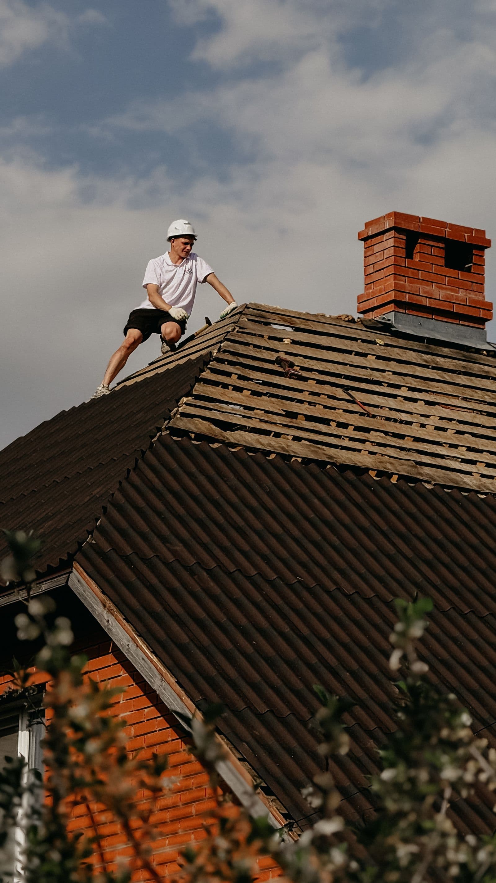 Inspector in a safety helmet assessing roof damage for a claim
