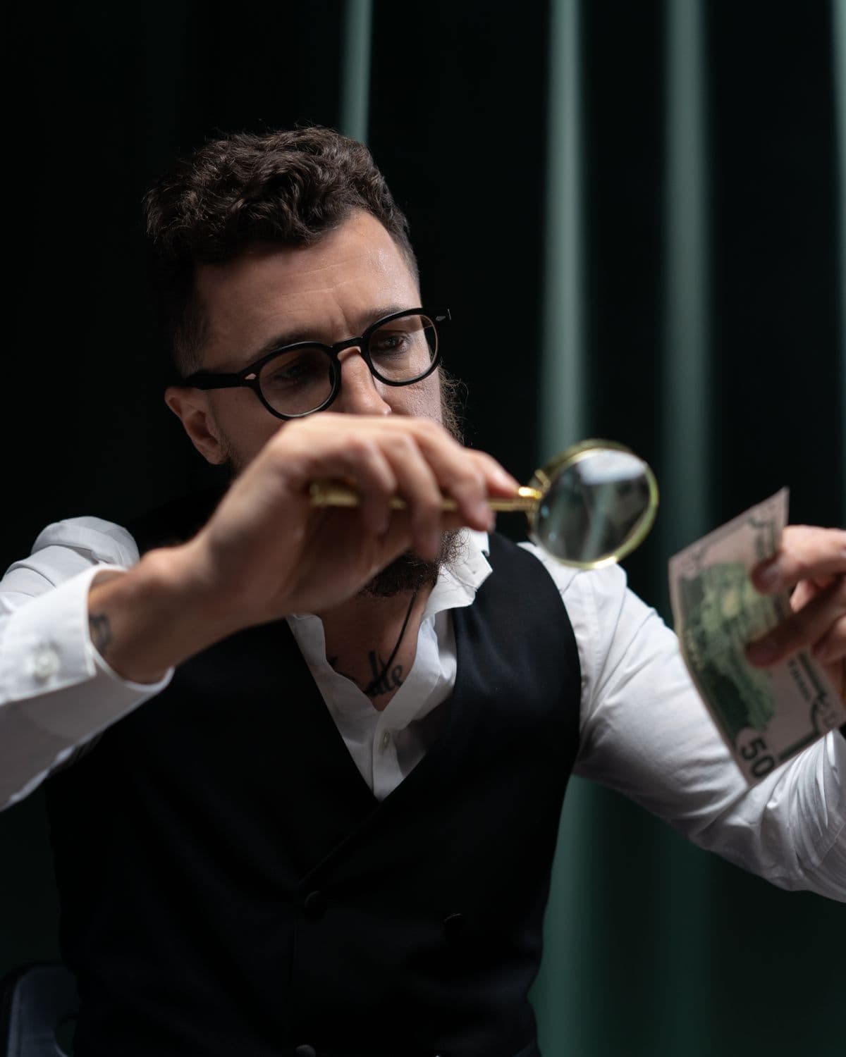 Person examining a banknote with a magnifying glass for authenticity